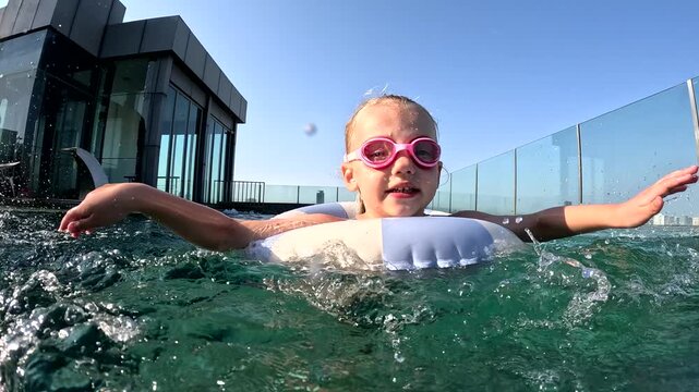 Kid enjoys swimming in rooftop pool on sunny afternoon in city