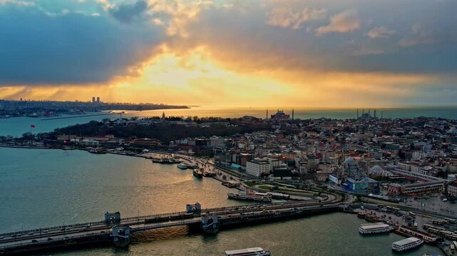Drone footage showing the Galata Bridge, Sarayburnu, Topkapi Palace, Hagia Sophia, the Blue Mosque and the Golden Horn illuminated by dramatic sunset colors over Istanbul.