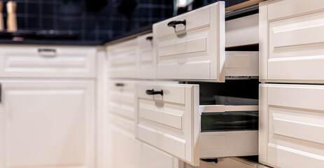 Open drawer in modern kitchen with tile wall. Storage design.
