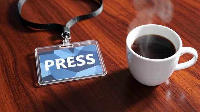 Overhead still life displays press badge on dark wooden conference table, positioned next to steaming ceramic coffee cup. Professional press badge symbolizes access and journalism.