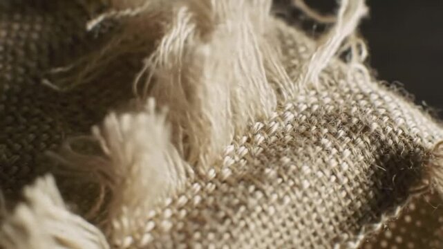 Rough woven fabric with frayed edges and loose threads shows texture.