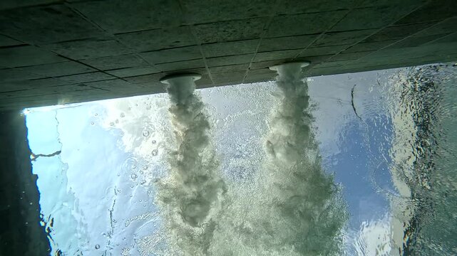 Water flows from pipes in a clear pool on a sunny day