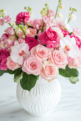 Charming bouquet of pink roses, orchids, and mixed blooms in a white vase