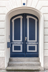 Fototapeta premium Dark blue classic door with molding on old house. Stylish urban entrance.