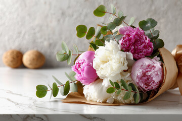 Pink and White Peony Bouquet Wrapped in Kraft Paper with Eucalyptus on White Marble