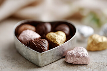 Heart Shaped Chocolates in Silver Tin Box with Foil Wrapped Treats on Gray Surface