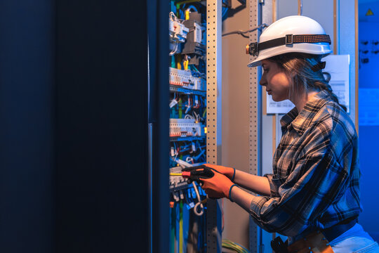 Electrician woman performs manual switchgear inspection. Technical maintenance.