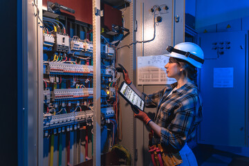 Electrician works with industrial switchgear and tablet. Digital inspection.