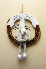 wicker wreath with a soft deer toy and welcome inscription on the wall