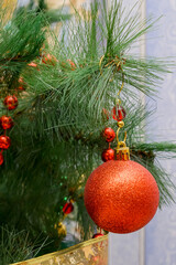 red shiny ball hanging on a branch of an artificial spruce