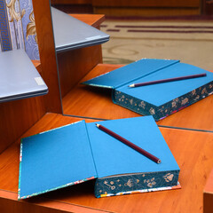 blue notebook with a pencil on a table next to a laptop