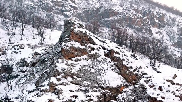 A dramatic aerial view of snowy rocky ridges and winter mountain slopes in Munzur Valley. Perfect for nature, winter landscapes, geography visuals and cinematic drone footage.
