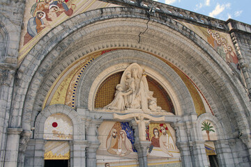 Obraz premium Entrance of the Basilica of Our Lady of Lourdes with mosaic artwork depicting Jesus, Mary, and saints, taken in July 2024.