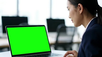 Professional Woman Engaged with Laptop Featuring Green Screen in Modern Office Environment.