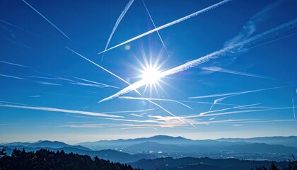 Contrails in a Blue Sky with Sun and Mountains.