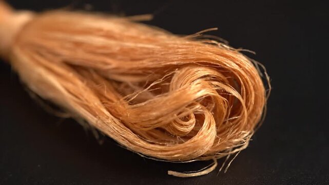 Close-Up of a Twisted Hank of Golden Brown Silk Threads on a Dark Background Soft Lighting Fibers and Swirls Elegant