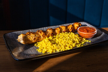 Bulgur pilaf with special spices, grilled beef kebab served with special tomato sauce on blue plate. Side view, close up