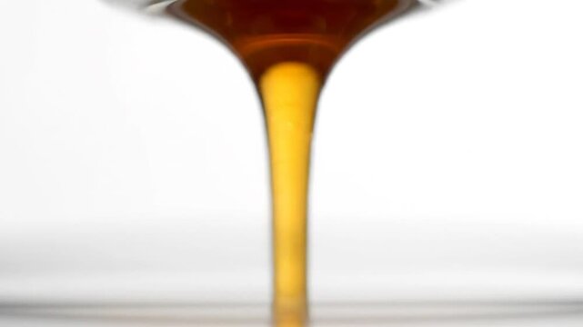 Golden Liquid Pouring Against Bright White Background Close Up Shot of Dripping Honey Golden Syrup Maple Syrup