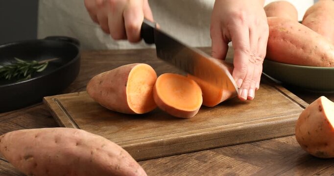 Woman cutting sweet potato at wooden table, closeup