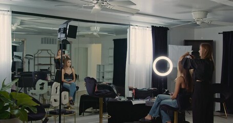 A wide moving shot of the hairstyling process in a beauty salon with black-and-white interior design