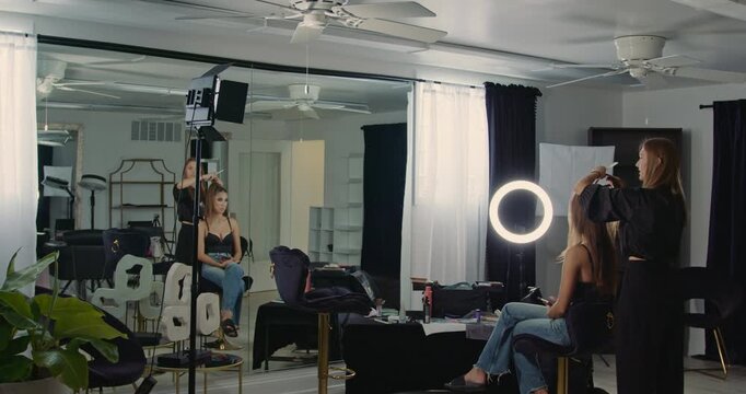 A wide moving shot of the hairstyling process in a beauty salon with black-and-white interior design