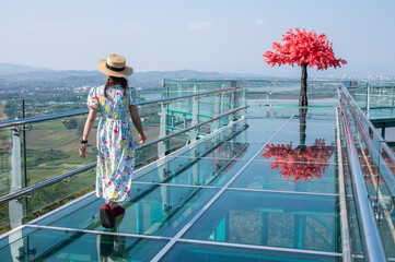 Rear view of tourist while walking on the skywalk in Wat Phrathat Pha Ngao temple for viewing Thailand and Laos border across Mekong river.
