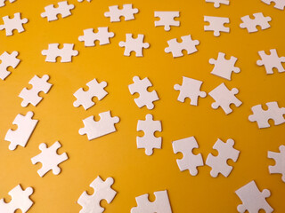 Naklejka premium Pieces of a&nbsp;jigsaw puzzle&nbsp;scattered across a yellow background