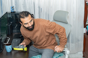 Person adjusting headphones while seated at desk with computer and coffee mug.