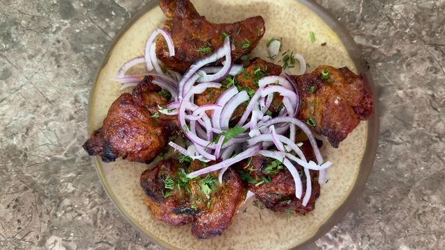 crispy grilled chicken wings on plate, topped with thinly sliced red onion and parsley, charred edges glazed with smoky marinade, rustic stone surface, closeup foodporn shot