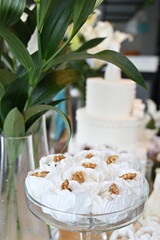 Artisanal walnut sweets in white floral paper liners, elegant wedding dessert table with glass stand, close up of gourmet nut confections for reception, sophisticated party sweets display