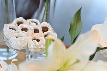 Gourmet chocolate brigadeiros in white lace paper liners, elegant sweet table for wedding reception, close up of artisanal cocoa truffles on glass stand, sophisticated party dessert display