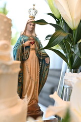 Statue of Our Lady with sacred heart and golden crown, religious Catholic figure for wedding altar decoration, close up of Virgin Mary icon with white lily flower in the foreground