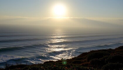 Obraz premium The image depicts a serene ocean scene during either sunrise or sunset, with the sun positioned low on the horizon and casting a bright reflection across the water