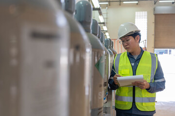 Industrial safety inspector checks gas cylinders in a factory warehouse, recording inventory and compliance to ensure workplace safety, quality control and efficient operations IT
