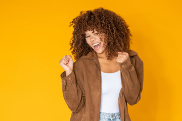 young woman with afro hair dancing, excited with joy, isolated