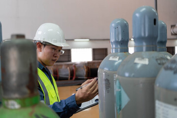 Engineer auditing gas cylinders in a substation warehouse, verifying labels, conditions, and inventory records while documenting safety compliance for critical electrical maintenance operations.