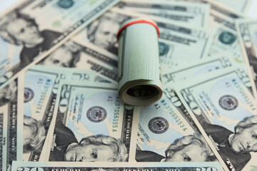 The cash roll represents American currency, over the spread of $20 bills, associated with savings, transactions, banking, and everyday financial use.