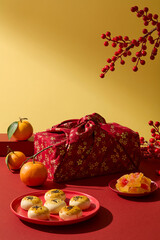 Lunar New Year creative scene with gift bag, lucky fruits and traditional snacks decorated on...