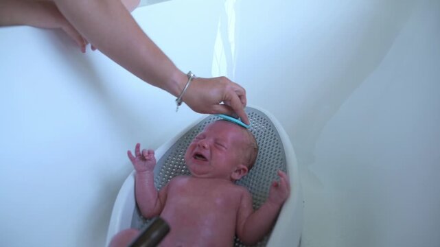 Softly washing baby with gentle hands, Careful and tender cleaning procedure for delicate infants, Performing gentle and loving bath routine for newborns with utmost care