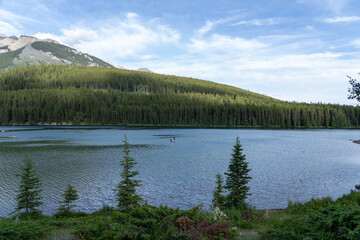 Wide view of people paddleboarding on the turquoise waters of Johnson Lake in the Canadian Rockies
