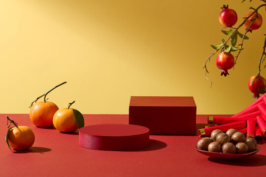 Festive Lunar New Year tabletop with red podiums, fruits and traditional snacks decorated. Clean background for commercial use, space for product presentation