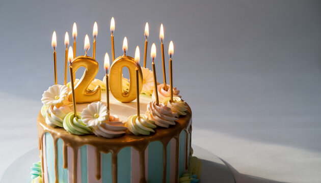 Twenty candles on a birthday cake with drip icing and decorative swirls
