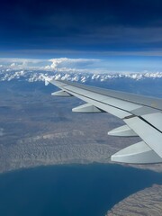 Obraz premium Aerial view from an airplane showing mountains and a body of water below. Scenic landscape capturing natural terrain from above.