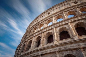 Fototapeta premium Ancient amphitheater's facade under a dynamic, streaking blue sky