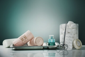 First aid medical kit and emergency supplies on a white surface with green studio background. Healthcare, safety, and emergency preparedness concept for clinics, hospitals, and home care.