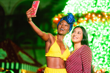 Diverse women friends taking selfie at illuminated park event