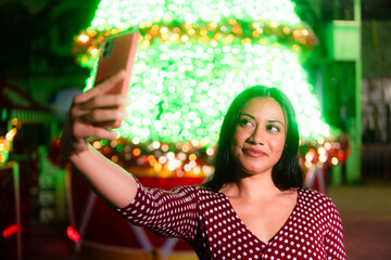 Latina woman taking selfie celebrating holiday event at night