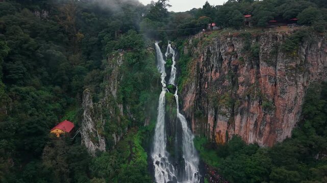 High waterfall cascading through lush green canyon