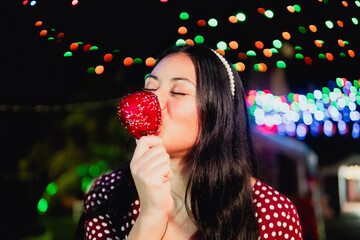 Woman enjoying sweet candy apple at night festival