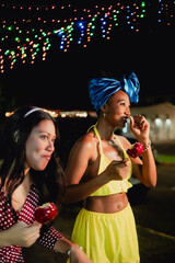 Diverse women friends enjoying candied apples at night